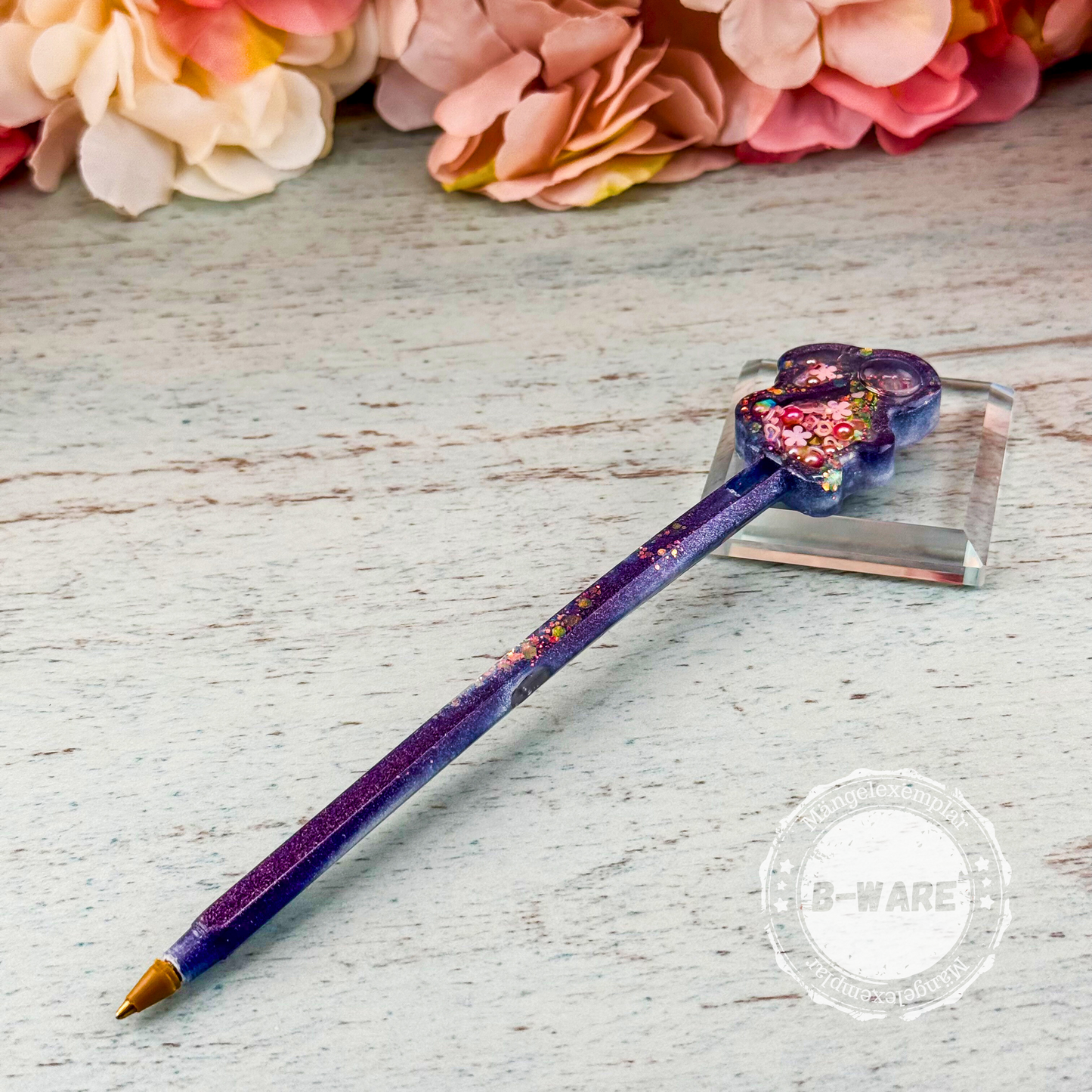 Handgefertigter Resin-Stift mit lila-schimmerndem Schaft und Hasen-Shaker, quer liegend mit sichtbarem B-Ware-Stempel