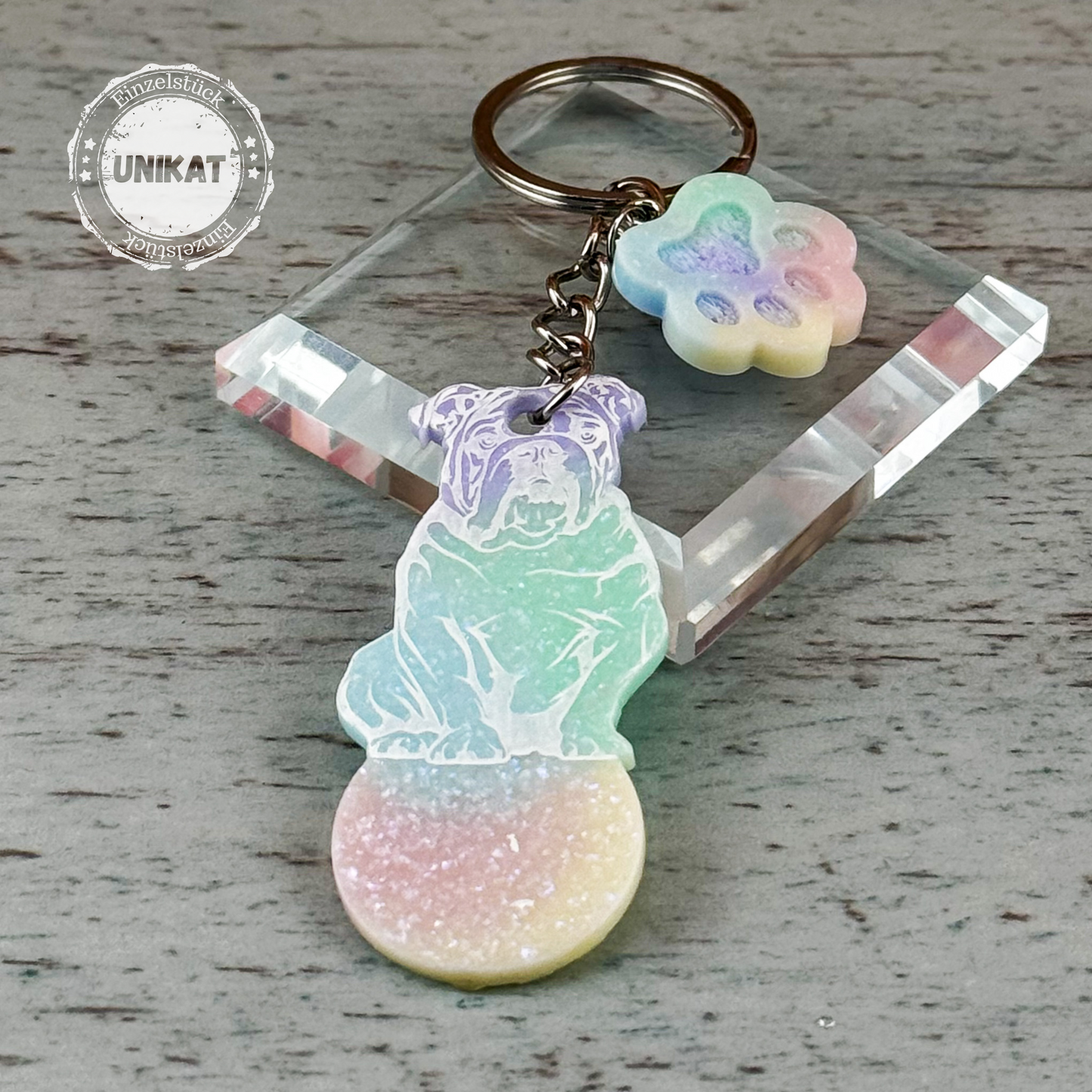 Handgefertigter Wagenlöser mit Bulldoggen-Motiv in Pastellfarben auf Glasunterlage, daneben ein Stempel mit der Aufschrift „Einzelstück“ – zeigt das Produkt als Unikat.